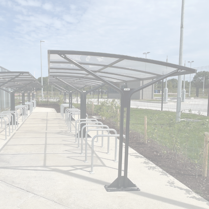 Bicycle parking area with covered shelters and racks on a sunny day.